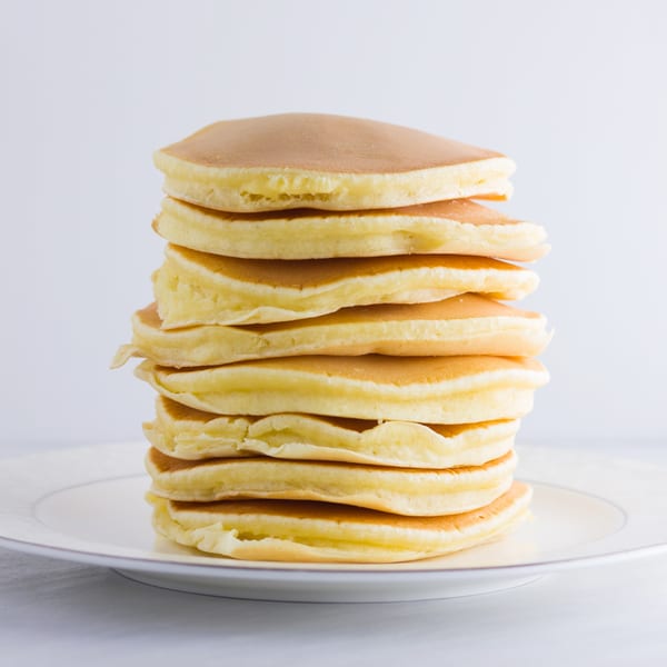 A tall stack of golden-brown pancakes on a white plate, ready to be served at Steve's Place.