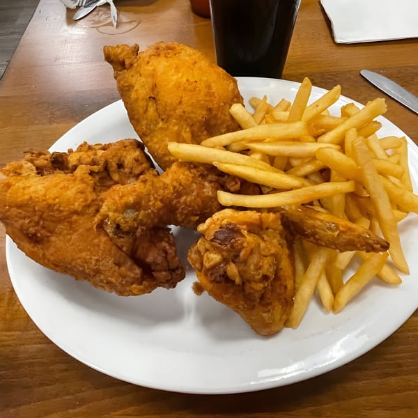 A white plate of golden-brown fried chicken pieces and a pile of crispy french fries.