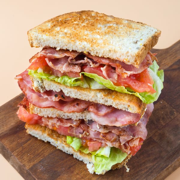 A towering BLT sandwich with toasted bread, crispy bacon, fresh lettuce, and ripe tomatoes.