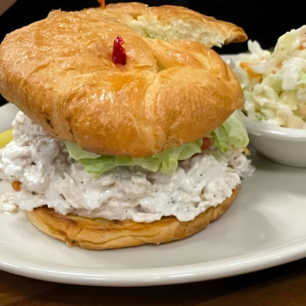 Chicken salad sandwich on a croissant with lettuce and a side of coleslaw at Steve's Place.